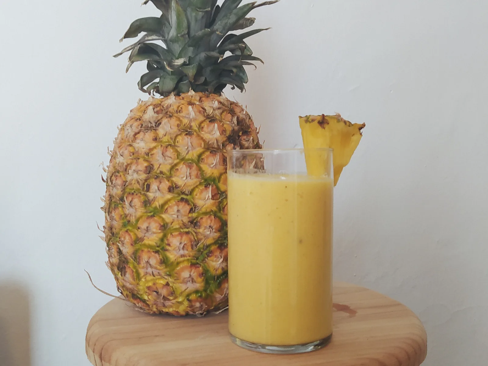 Pineapple smoothie next to a whole pineapple